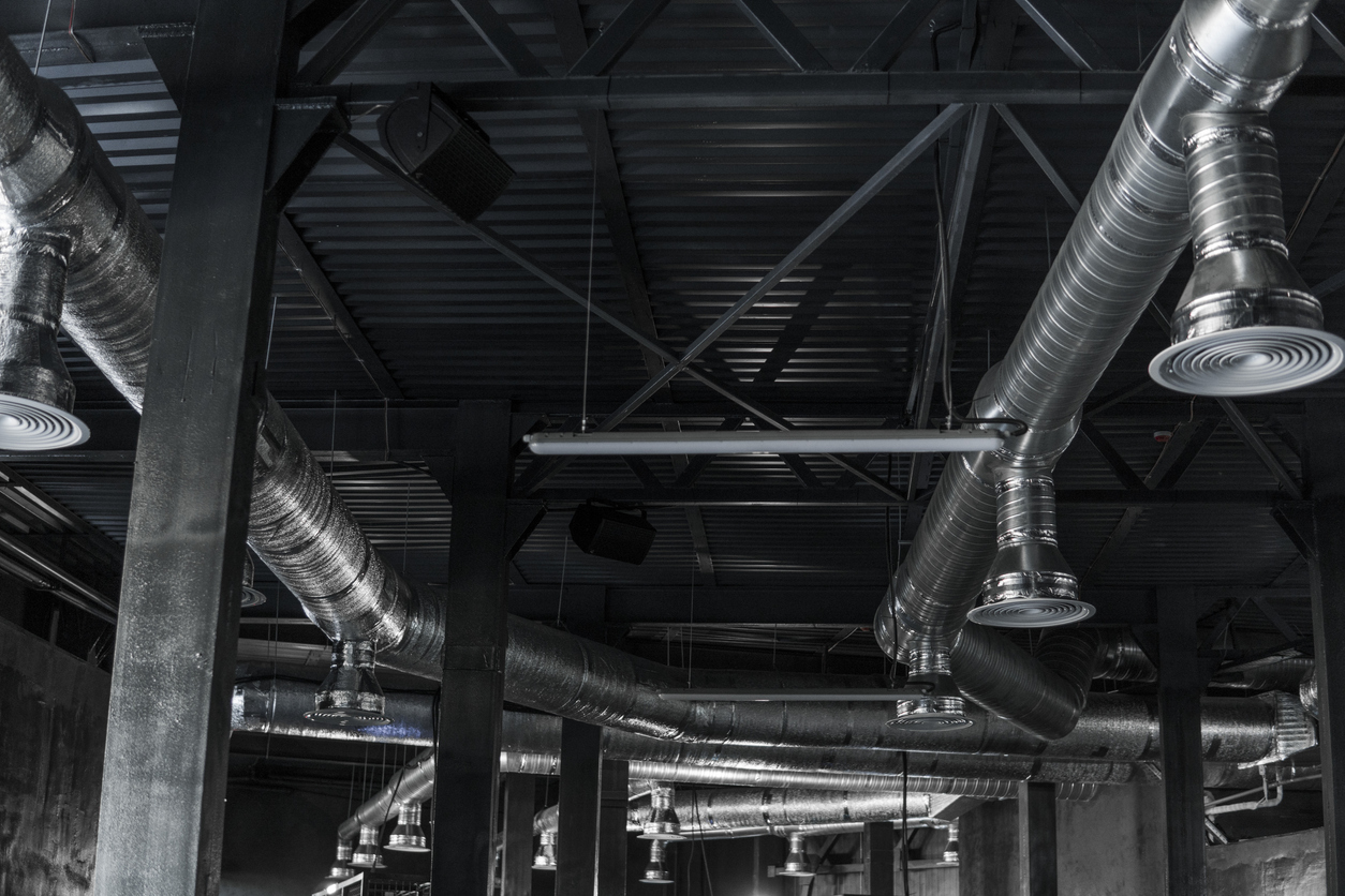 Ventilation system on the ceiling of large buildings. Ventilation pipes in silver insulation material hanging from the ceiling inside new building.